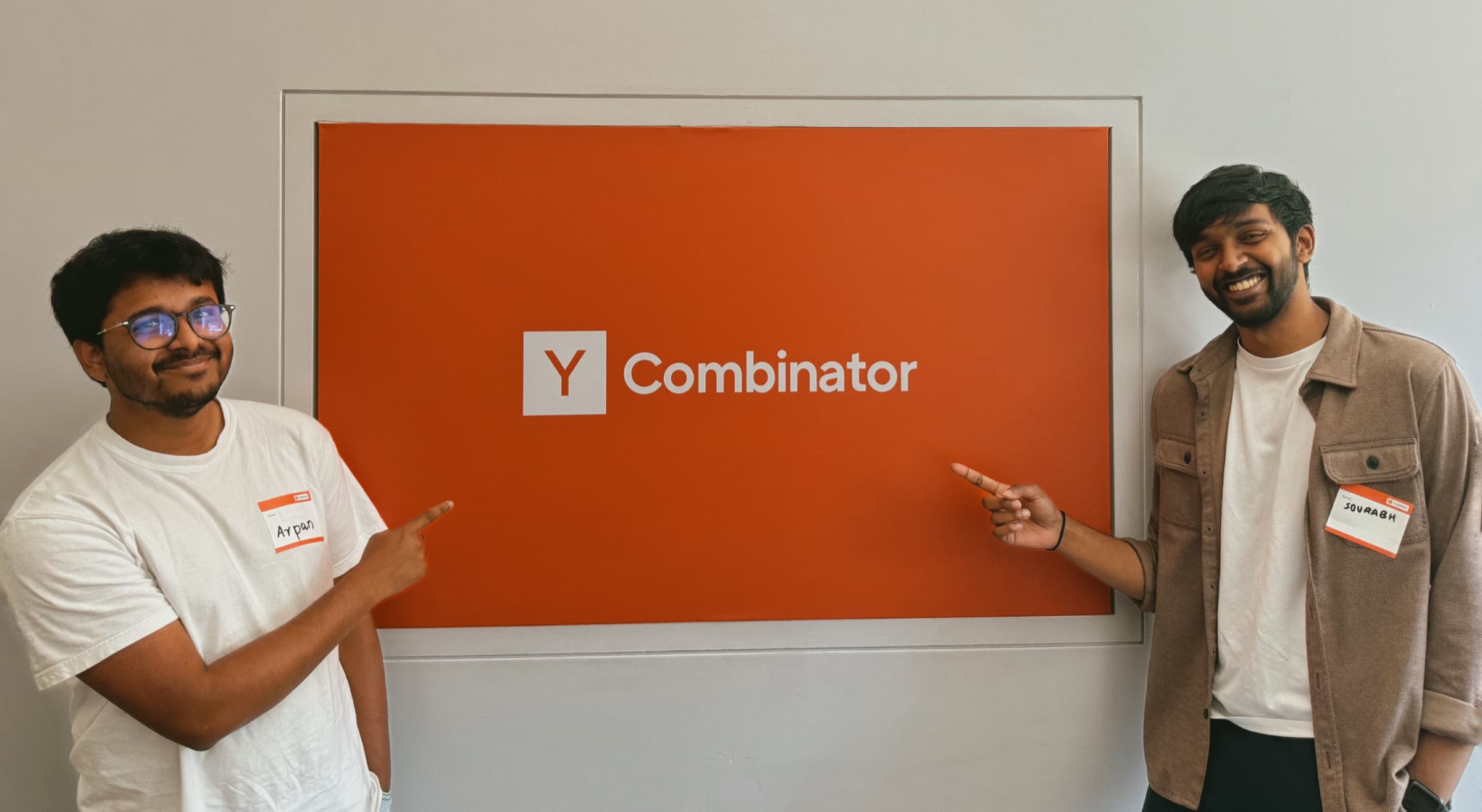 Sourabh and Arpan smiling and pointing at a Y Combinator sign