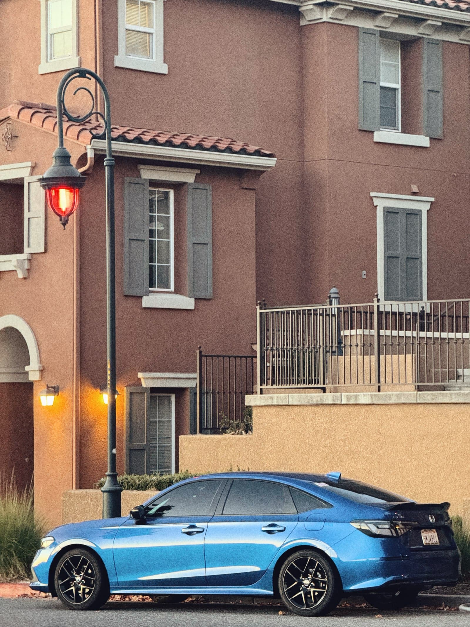 Blue Honda Civic parked by Mediterranean townhouses at dusk