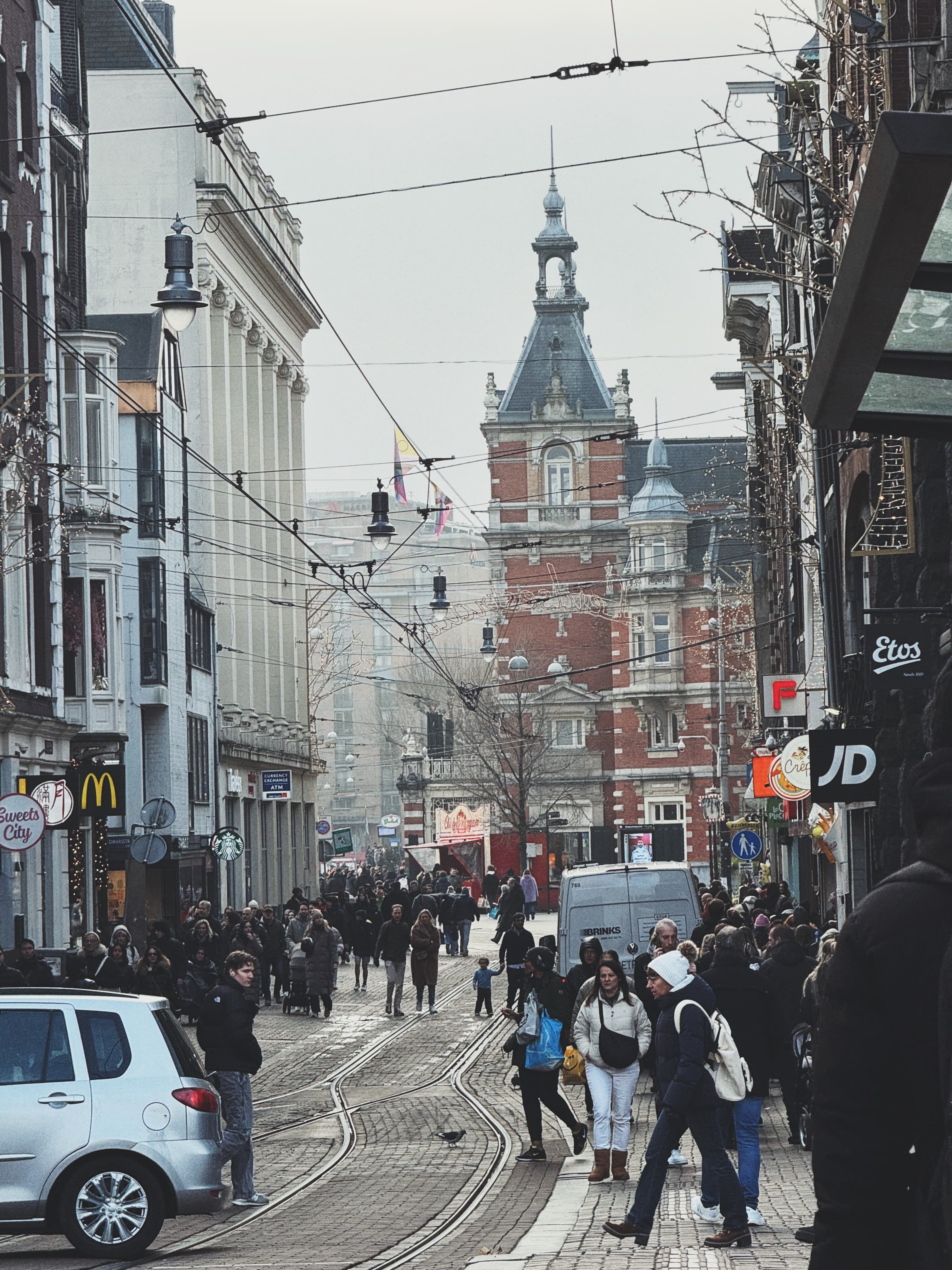 Crowded Amsterdam street with historic spire and shopfronts