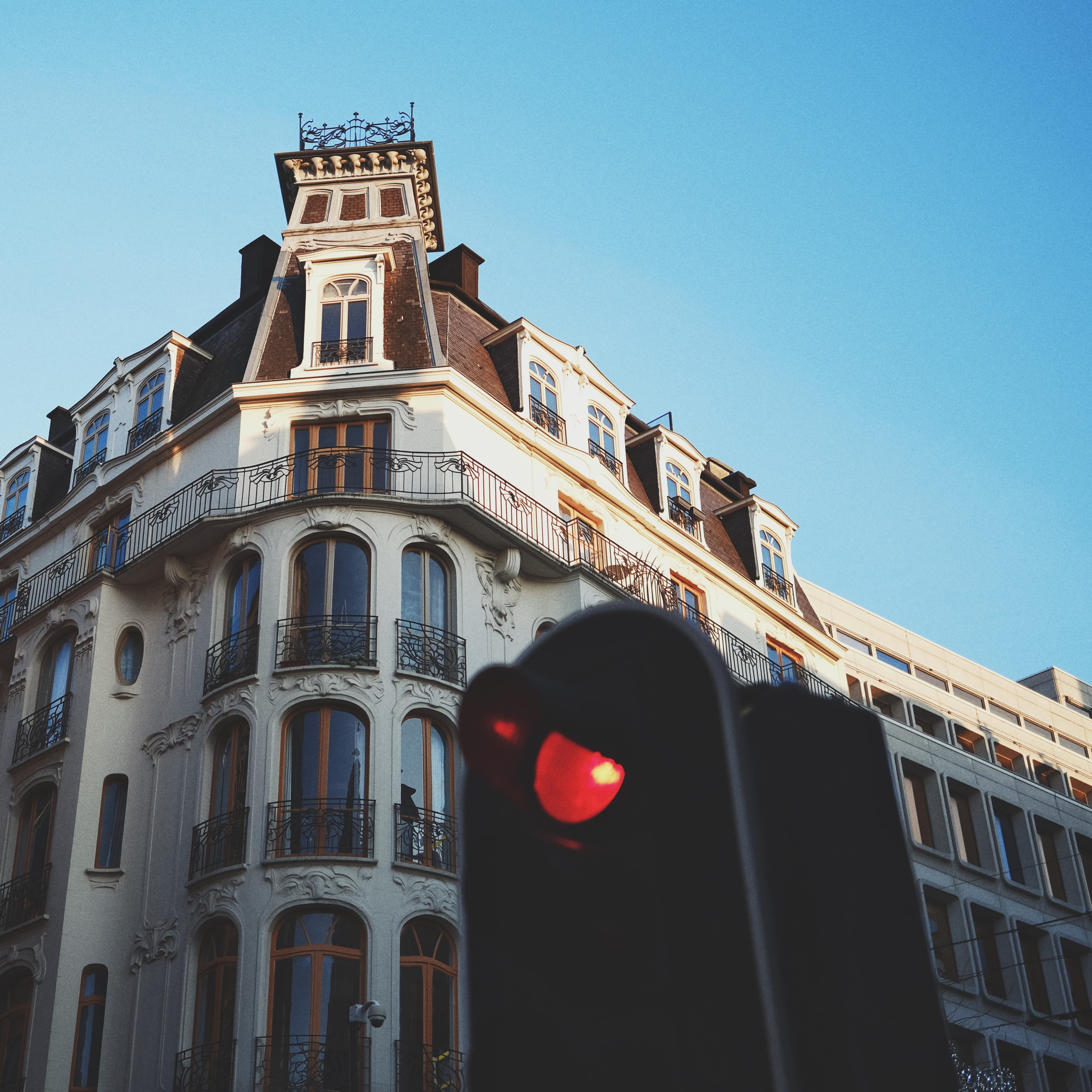 Ornate Belgian corner building with a red traffic light in the foreground